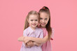 © New Africa - Portrait of cute little sisters on pink background