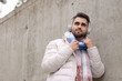 © New Africa - Handsome man in warm scarf and headphones near wall outdoors. Space for text