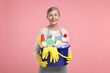 © New Africa - Happy housewife holding bucket with cleaning supplies on pink background