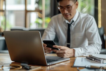 Canvas Print - A man using a laptop and phone at table