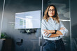 © Jacob Lund - Young female professional standing in front of a meeting area in a business office