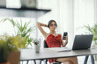 © StockPhotoPro - Young woman sitting at desk and using her smartphone