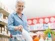 © StockPhotoPro - Senior woman putting goods in the shopping cart
