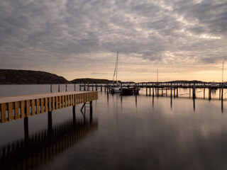 Poster - Sunset pier reflected in calm waters with a small dock