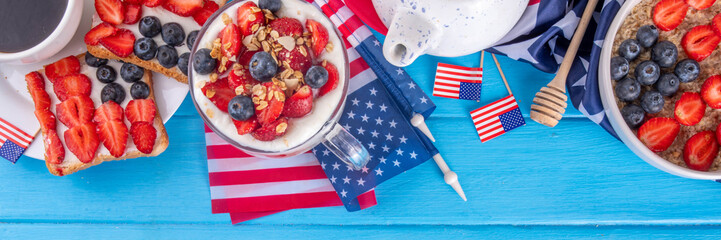 USA patriotic breakfast or brunch with american flag decorated oatmeal, layered yogurt granola dessert, toast sandwiches with fresh berries, and coffee cup on kitchen garden table