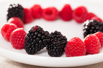 Wall Mural - Raspberries and blackberries laid out on a white plate in circle