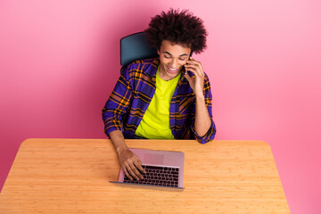 Poster - Photo of worker guy sit table speak phone working laptop isolated pastel color background