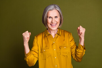 Sticker - Photo of cheerful lucky lady dressed blouse rising fists empty space isolated khaki color background