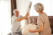 © Dusan Petkovic - Happy senior couple standing on a bed at home and having fun with pillow fight.