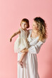 © LIGHTFIELD STUDIOS - A lovely mother in white with curly hair holds a baby in a white dress.