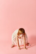 © LIGHTFIELD STUDIOS - Little girl in white dress posing in motion on pink backdrop.