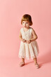 © LIGHTFIELD STUDIOS - Little girl in white dress poses on pink background.