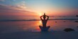 © kiimoshi - The silhouette of a woman doing yoga on the beach at sunset.