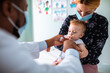 © Marko Geber - Pediatrician administering oral medication to an infant held by mother