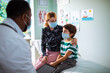 © Marko Geber - Pediatric doctor consulting with young boy and his mother in clinic