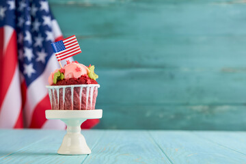 Patriotic cupcake 4th july with american flag. Delicious cupcake with cream cheese and blue and red toping on old blue wooden background. Dessert food for American Independence Day celebration.