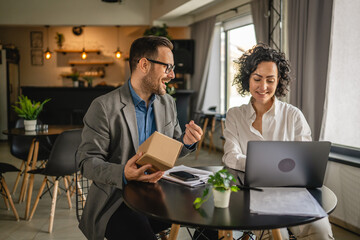 woman and man colleagues check shipment on laptop at cafe