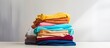 © vxnaghiyev - A pile of colorful cotton clothes neatly folded on a white table with an empty copy space for placement