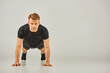 © LIGHTFIELD STUDIOS - A young athletic man in active wear performing push ups on a white background, showcasing strength and fitness.