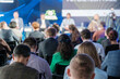 © Anton Gvozdikov - Diverse audience attentively listening to a panel discussion at a business conference with a focus on technology and innovation.