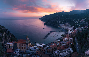 Poster - A panoramic view of the picturesque cityscape of Amalfi Coast, showcasing its colorful buildings and lush greenery along the coastline at sunset