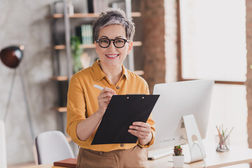 Photo of nice senior woman sit documents dressed yellow formalwear executive business leader work in cozy beautiful office interior