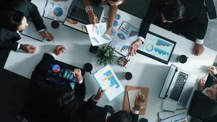 Wall Mural - Top down aerial view of skilled businessman pointing financial chart at whiteboard while smart investor listening presentation and analyze stock market investment graph at meeting table. Directorate.