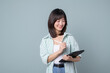 © Jirawatfoto - Portrait of young asian woman, teacher or student with digital tablet and pencil, writing, taking notes, doing her homework, standing over green background
