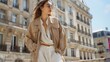 © mashimara - Photo of a fashionable young woman in a beige jacket and white outfit posing confidently on a sunny city street. Modern urban style and street fashion.