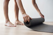 © kite_rin - Woman rolling up exercise mat and preparing practicing yoga. Young woman is going meditating or doing exercises at home. Relaxation, body care, healthy lifestyle, workout, sports training concept