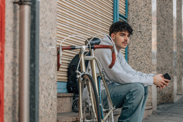 Wall Mural - urban cyclist sitting on the street with mobile phone