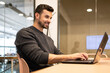 © ADDICTIVE STOCK - Smiling Man Working on Laptop in Coworking Space