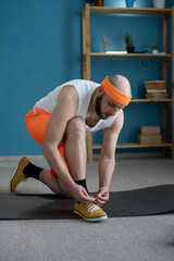 Wall Mural - In a retro fitness setting, a man ties his shoelaces in a home gym, preparing for a workout