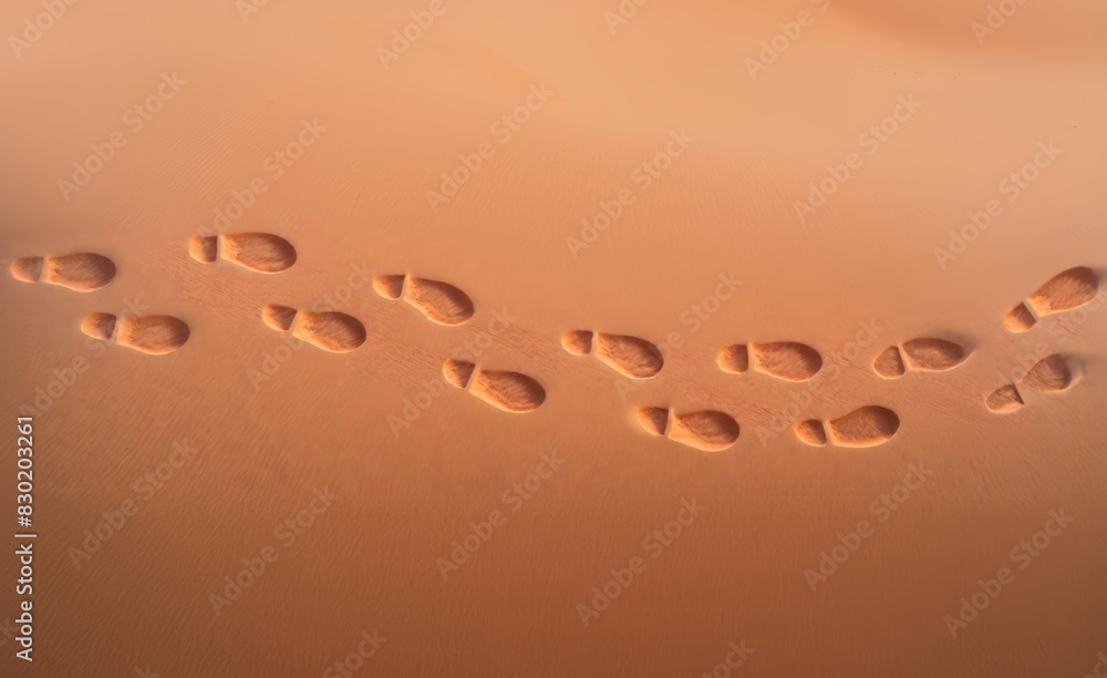 Overhead view: a trail of distinct shoe prints in the sand in a desert ...