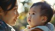 © Emin - An Asian toddler gazes lovingly at his mother outdoors on a sunny day