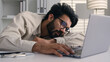 © Yuliia - Lazy weary sleepy male manager tired exhausted Arabian Indian businessman employee working computer boring remote job man fall sleep on desktop napping in office overwork fatigue no energy sleeping