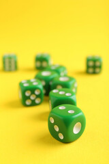 Canvas Print - Many green game dices on yellow background, closeup