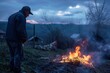 © Road Red Runner - A man stands beside a roaring fire in a vast field, tending to the flames with a deep concentration.