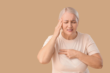 Wall Mural - Mature woman suffering from breast pain on brown background. Cancer awareness concept