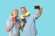 © Pixel-Shot - Mature couple with passports taking selfie on blue background. Travel concept