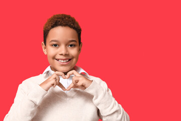 Sticker - Cute little African-American boy showing heart gesture on red background. Valentine's day celebration