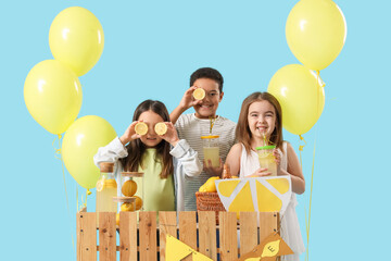 Wall Mural - Cute little children with lemons at lemonade stand on blue background