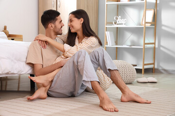 Poster - Happy loving young couple sitting near bed