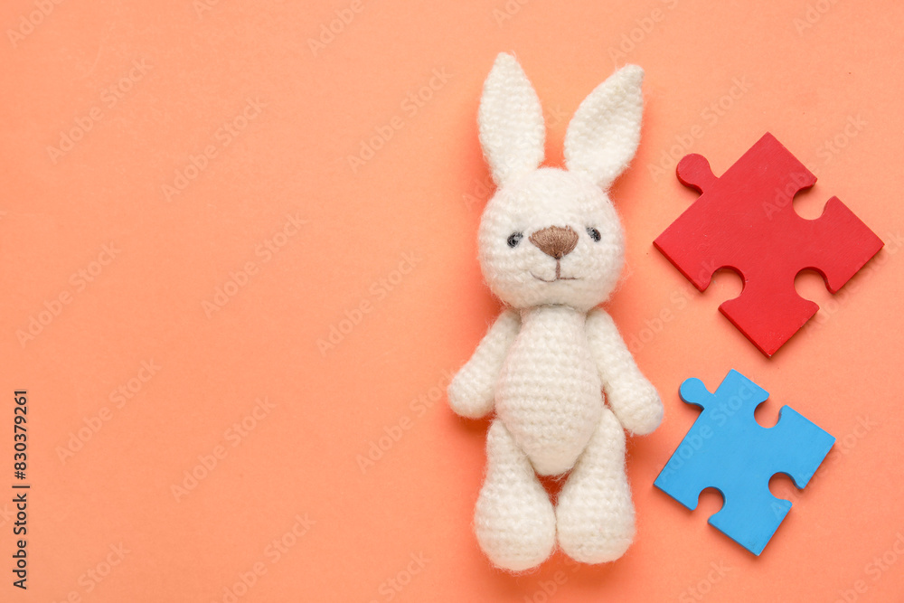 Colorful puzzle pieces and toy bunny on orange background. Concept of autistic disorder. Top view