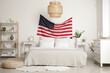 © Pixel-Shot - Interior of light bedroom with USA flag above cozy bed