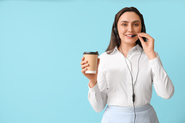 Canvas Print - Female technical support agent in headset with paper cup of coffee on blue background