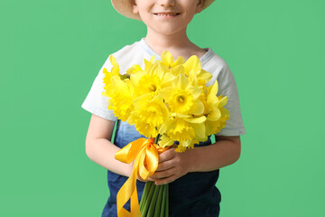 Wall Mural - Cute little happy boy with bouquet of beautiful narcissus on green background, closeup