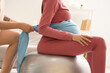 © Pixel-Shot - Doula with scarf massaging pregnant woman on fitball at home, closeup
