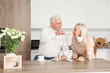 © Pixel-Shot - Mature couple with tea and cake celebrating their wedding anniversary in kitchen