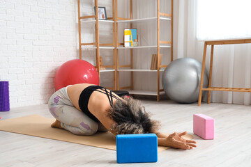 Wall Mural - Sporty mature woman with blocks doing yoga on mat in gym